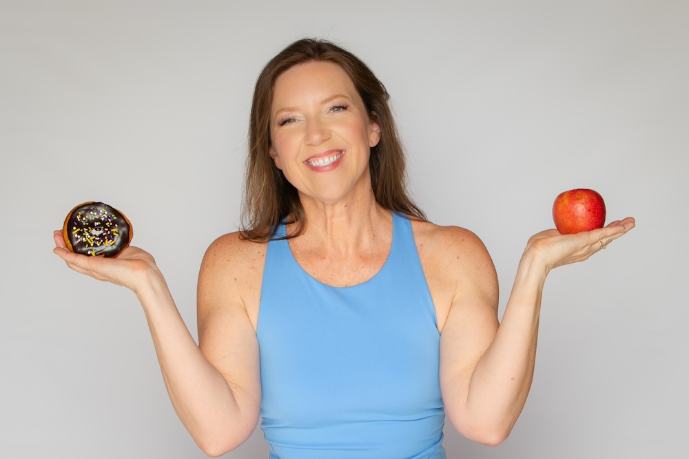 Stephanie holding an apple in one hand and a donut in the other